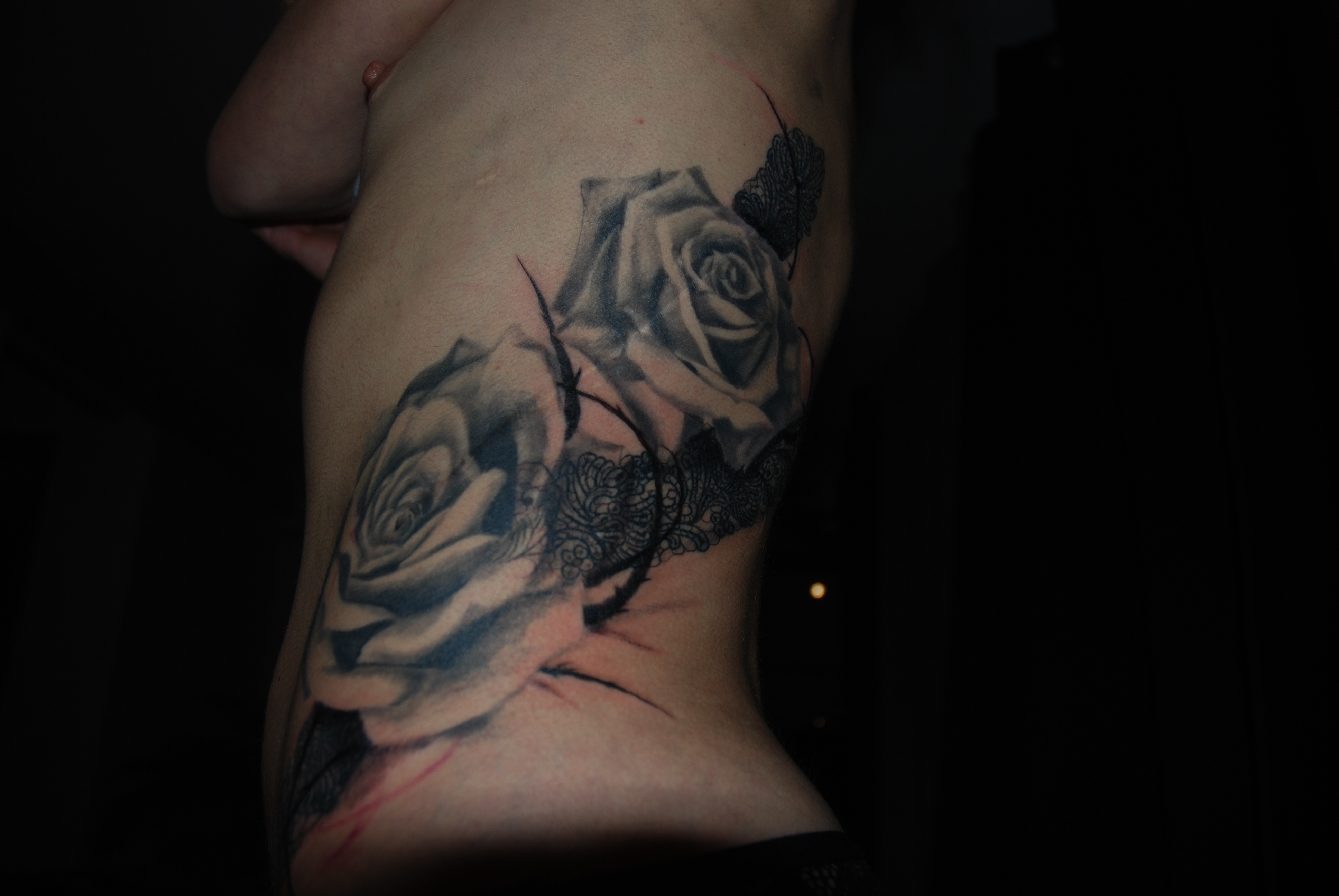 tatouage moderne de deux roses réaliste et de ronce graphique pour couvrir une cicatrice sur tout le flan gauche 